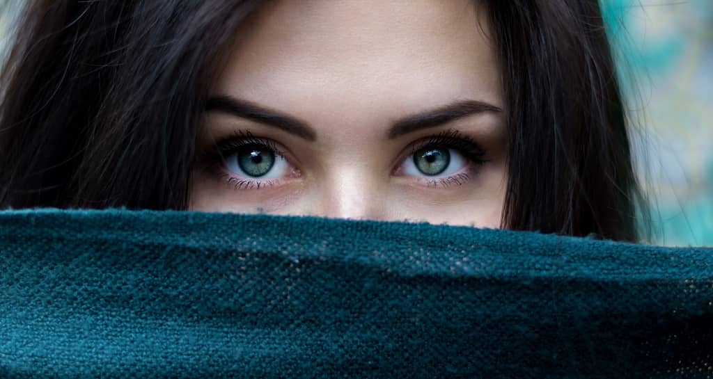 Brunette woman with green eyes, half-face covered